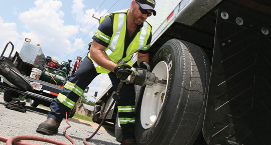 Image of a Goodyear technician installing a tire on a truck using a power wrench